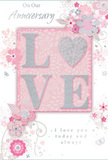 This anniversary card offers a gentle, heartfelt tribute to lasting romance, blending blush pastel pinks with cool silvery greys in a way that feels both intimate and refined, much like a quiet evening shared in a Gipsy Hill café. The focal point is the word LOVE, spelled out in soft, raised letters whose surfaces are coated in a fine, shimmering glitter. The letter O is replaced by a shining silver heart, textured and slightly domed, making it stand out as a luminous symbol within the word. Around this central motif, a constellation of delicate flowers blooms across the card. Their petals, tinted in blush, mauve, and hints of soft ivory, appear almost watercolour in their softness, with fine lines suggesting careful sketchwork rather than rigid outlines. Slender vines, tiny petals, and swirling flourishes intertwine between the blossoms, while subtle butterfly shapes or curved accents add a sense of movement, like petals and wings stirred by a light spring breeze rolling over the hill. The background remains a tender, even pink, providing a calm canvas that lets the silver and floral details shine. Near the top and bottom, the phrases On Our Anniversary and I love you today and always are written in an elegant script, the handwriting-style font looping smoothly and harmonising with the curves of the floral vines. The composition feels balanced yet softly whimsical, offering a keepsake that is as gentle as a whispered promise and as meaningful as a hand-delivered anniversary bouquet shared between two people who have grown together over time.